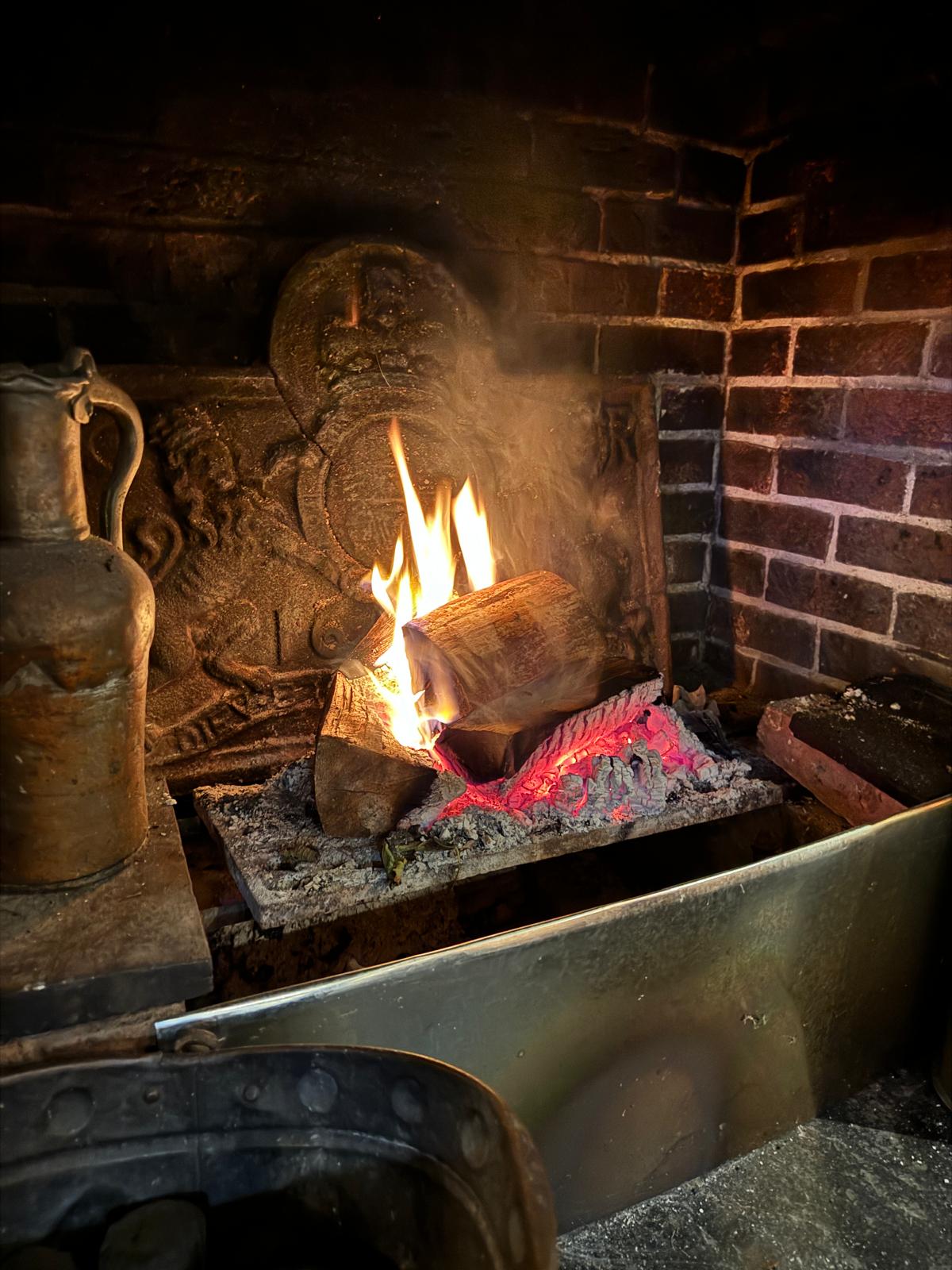 A welcoming open fire burning in the old brick hearth